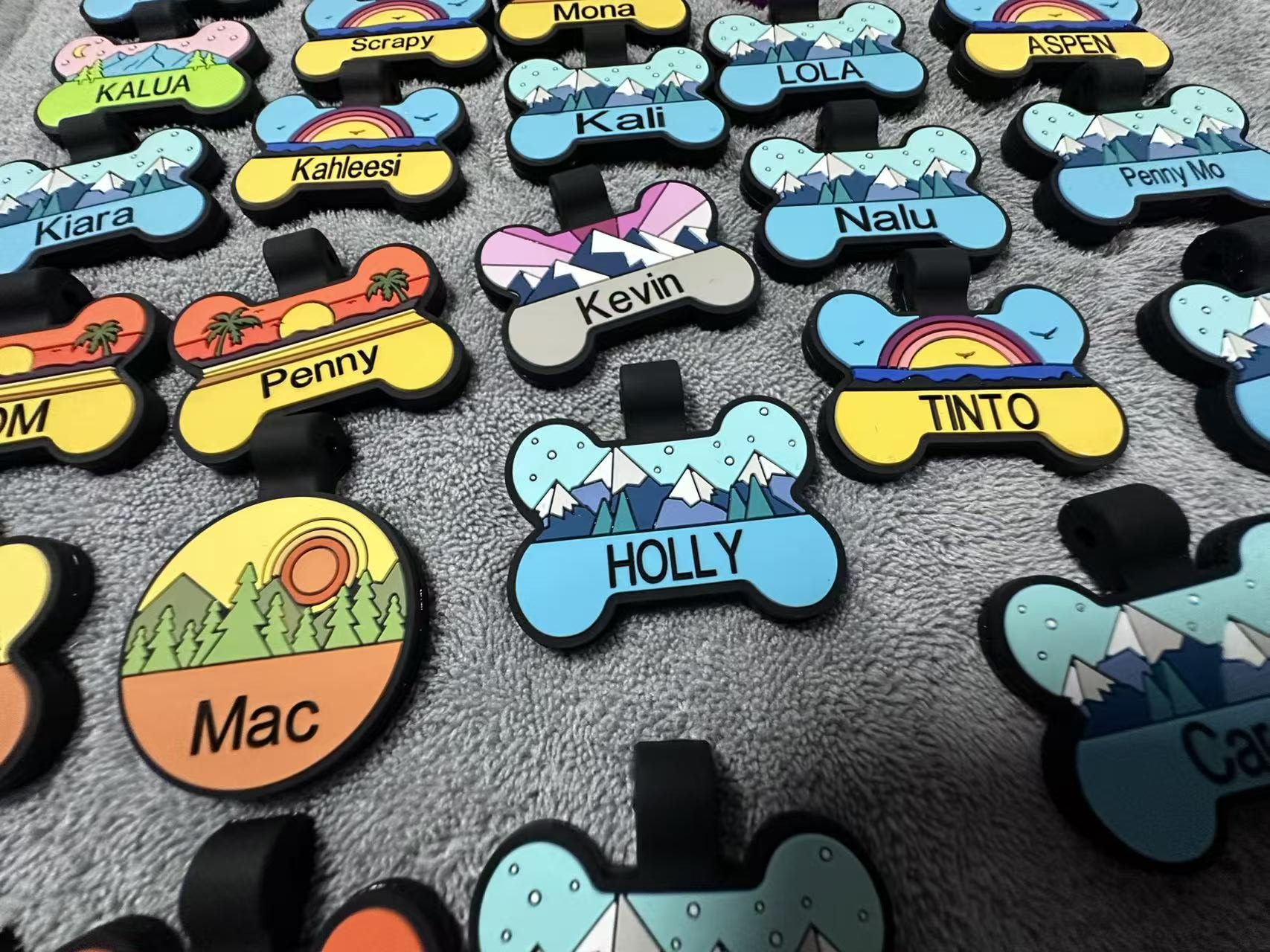 Custom silicone pet ID tags with personalized names — shown: HOLLY, Kaili, Kahlessi, Penny, Tinto, Mac, Lola, Nalu, Mona, Scapy, Aspen, Penny Mo, Kali, Kevin