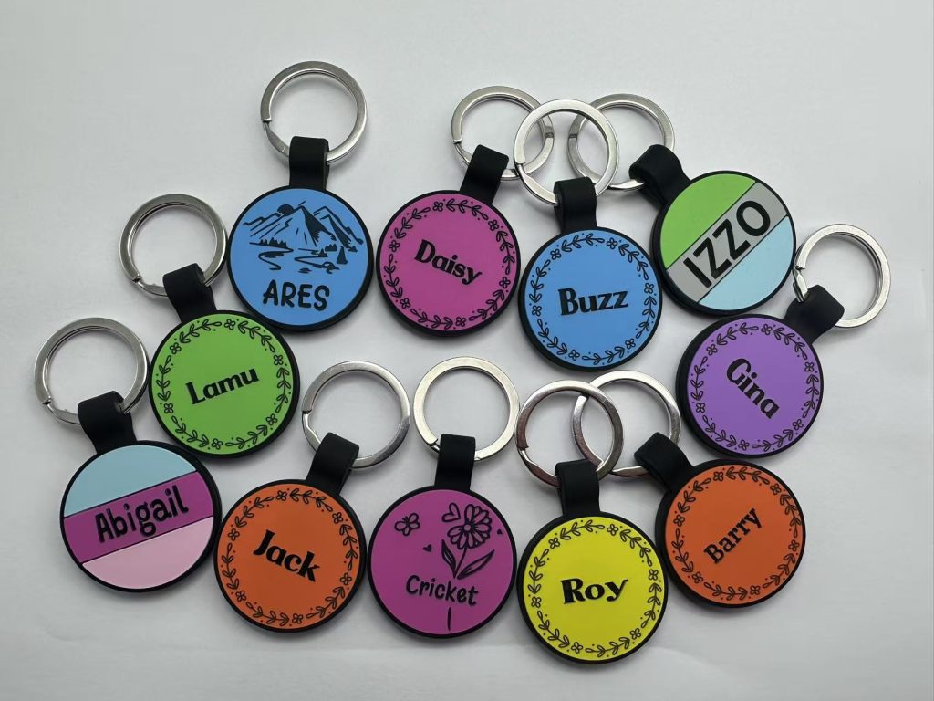 Custom round silicone pet ID tags with engraved names: ARES, Daisy, Buzz, IZZO, Lamu, Gina, Abigail, Jack, Cricket, Roy, Barry - multi-color flower wreath, landscape, and striped designs